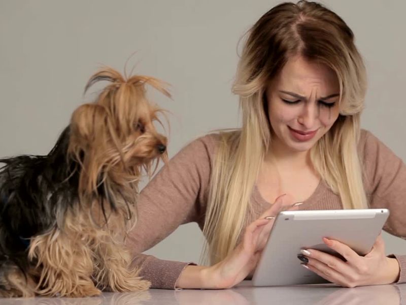 Uplakana devojka čačka tablet a pas stoji pored nje