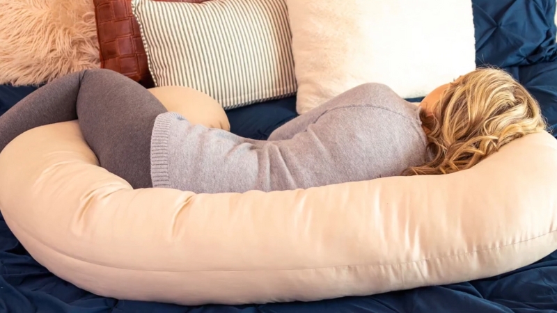 Žena leži udobno oslonjena na veliki jastuk za trudnice