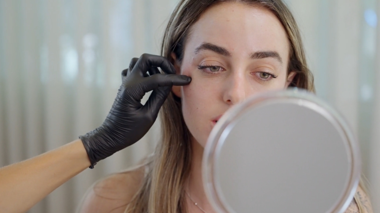 Dermatolog pregleda kožu lica žene tokom konsultacije.